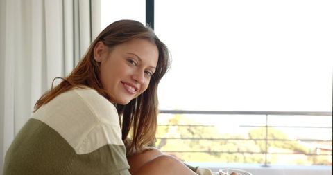 Woman Enjoying Relaxed Morning by Bright Window with Mug in Hand