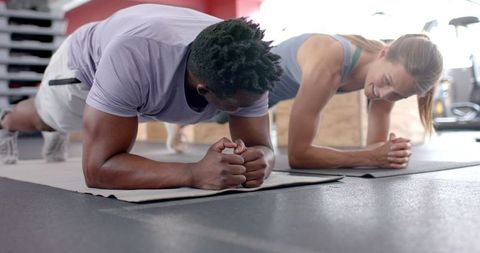 Diverse Fitness Enthusiasts Planking Together in Modern Gym