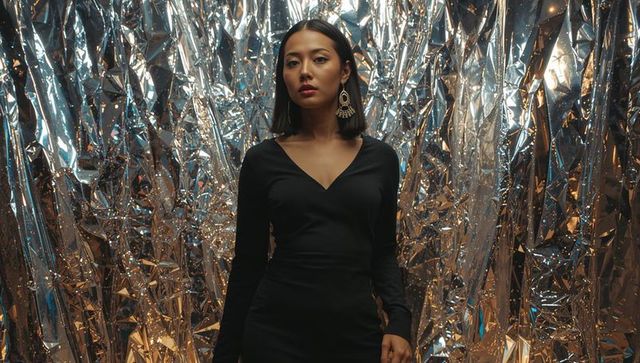 Fashionable model posing against shimmering metallic backdrop