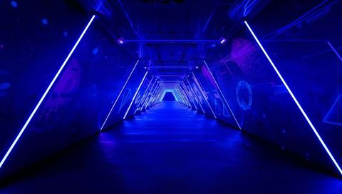 Neon triangular corridor leading toward futuristic vanishing point with blue led geometry