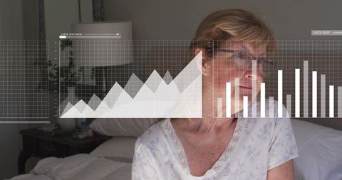 Senior woman sitting on bed wearing eyeglasses with overlaid health charts for telehealth
