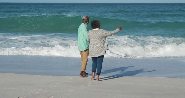 African american senior couple holding hands on beach by seaside with copy space. Retirement, lifestyle, vacation, summer, happiness, wellbeing concept, unaltered.
