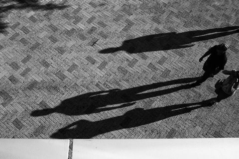 Abstract shadows of pedestrians on cobblestone street