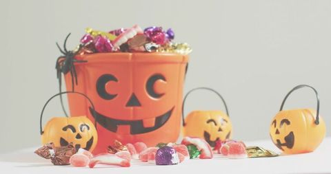 Bright pumpkin pail overflowing with halloween candy and small jack-o-lantern buckets