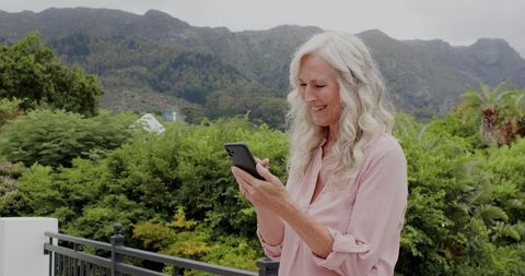 Woman Appreciating Scenic Mountain View with Smartphone Outdoors