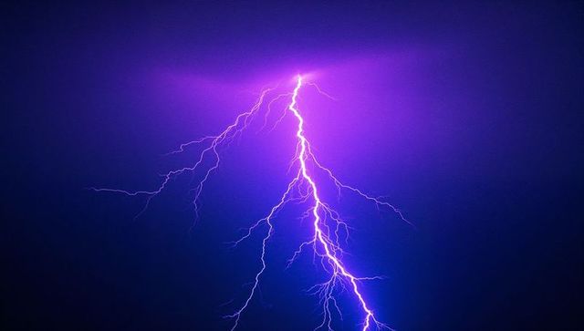 Vivid Purple Lightning Bolt Illuminating Stormy Night Sky