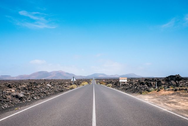 Empty Road Leading to Volcanic Mountains Under Clear Blue Sky - Download Free Stock Photos Pikwizard.com