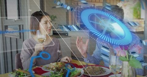 Couple sharing meal with holographic AR interface, Asian woman holding wine, man gesturing