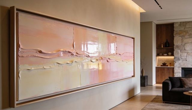 Displaying large horizontal pastel textured abstract painting framed in modern living room