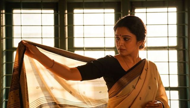 Indian woman adjusting sari pallu in golden backlight by lattice window, elegant portrait