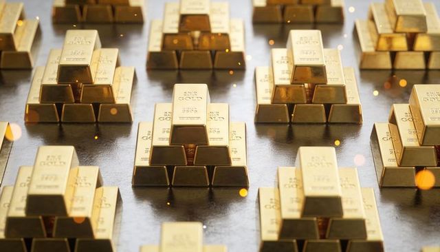 Shining gold bullion pyramid reflecting on glossy surface with warm bokeh