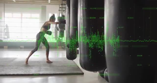 Female athlete practicing boxing at gym with animated data visualization overlay. Represents intersection of fitness and technology. Suitable for content on athletic training, tech in sports, or health monitoring equipment.