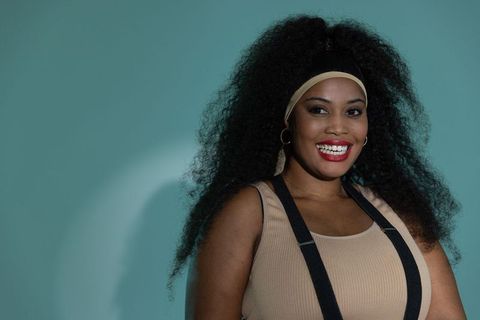 Confident african american woman smiling retro fashion teal backdrop gold hoops