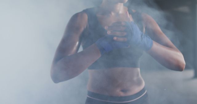 Determined Female Boxer with Blue Hand Wraps Training in Misty Session - Download Free Stock Images Pikwizard.com