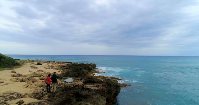 Couple Walking on Rocky Beach by the Ocean - Download Free Stock Images Pikwizard.com