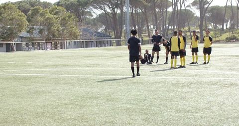 Teens Resting on Soccer Field After Practice on Sunny Day