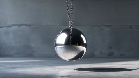 Polished metal wrecking ball with chain suspended in concrete chamber