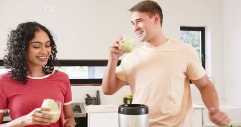 Happy Couple Enjoying Healthy Green Smoothies at Home