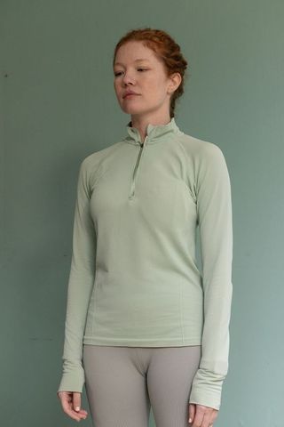 Woman wearing mint zip pullover and grey ribbed leggings minimalist activewear portrait