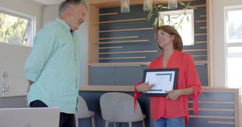Senior couple celebrating achievement with certificate at home
