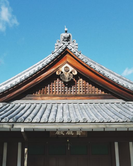 This image features a traditional Japanese temple roof under a clear blue sky. The intricate design and wooden structure highlight the rich cultural heritage and craftsmanship. Suitable for use in articles or projects related to Japanese culture, architecture, heritage sites, travel, and tourism promotions.