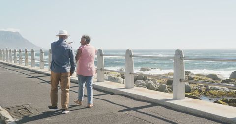 Senior Couple Strolling Along Seaside Promenade