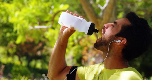 A young adult male is hydrating during a workout outdoors, with copy space - Download Free Stock Photos Pikwizard.com