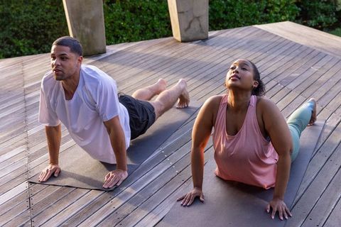 Diverse Couple Practicing Yoga Outdoors on Sunny Deck