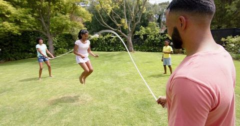 Family Playing Double Dutch in Sunlit Garden