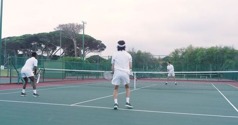 Doubles tennis players competing on outdoor hard court near net showing teamwork
