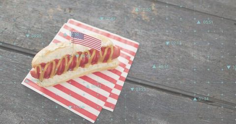 Sitting hot dog on rustic picnic table with american flag toothpick and ketchup mustard