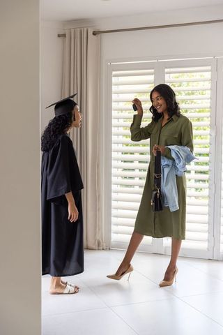 Graduate receiving keys from parent in light-filled home interior