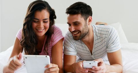 Happy Couple Relaxing in Bed Using Tablet and Smartphone - Download Free Stock Images Pikwizard.com