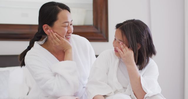 Image of happy asian mother and daughter in robes having fun. Family, motherhood, relations and spending quality time together concept digitally generated image.