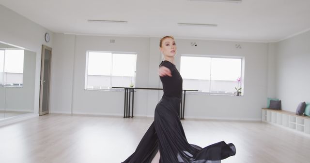 Focused caucasian female ballet dancer in long black dress practicing at dance studio, copy space. Dance, ballet, discipline, practice and training, unaltered.