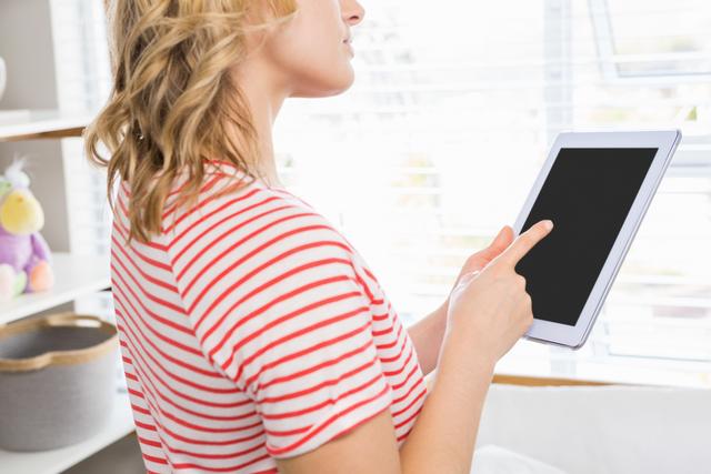 Mid-section of woman using digital tablet at home