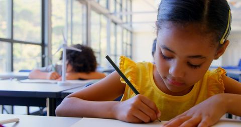 Diligent Schoolgirl Focused on Writing in Classroom - Download Free Stock Images Pikwizard.com