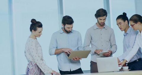 Modern professionals engaging in office collaboration with laptops