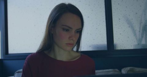 Woman Typing on Laptop in Modern Home with Rainy Window