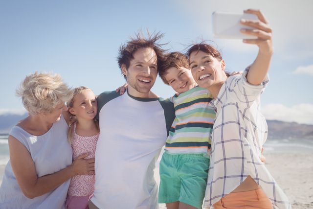 Family enjoying a sunny day at the beach, capturing a joyful moment with a selfie. Perfect for promoting family vacations, summer holidays, travel destinations, and outdoor activities. Ideal for use in advertisements, brochures, social media campaigns, and family-oriented content.