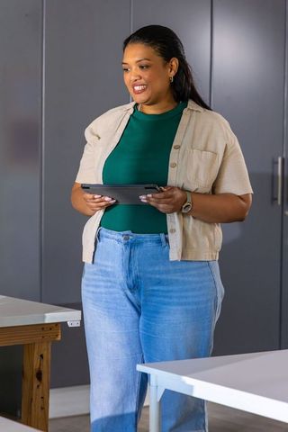 African-american woman holding tablet in modern studio workspace smiling and collaborating
