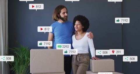 Young Couple Interacting With Social Media Icons In New Apartment