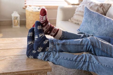 Couple reclining on sofa with cozy patterned socks and jeans on wooden coffee table