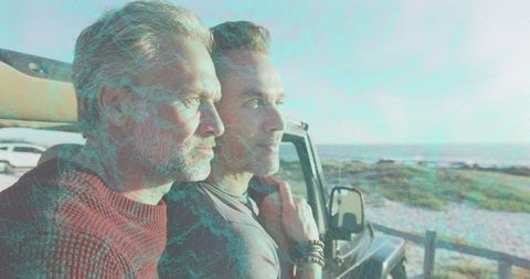 Mature men standing at coastal lookout near suv embracing quiet road trip companionship
