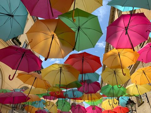 Vibrant umbrellas floating above pedestrian street creating colorful overhead canopy