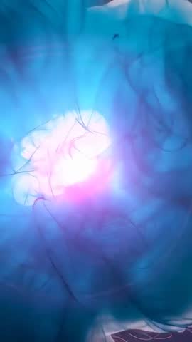 Glowing turquoise LED cloud showing drifting fibers and magenta halo in vertical video