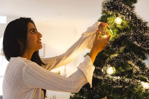 Woman decorating christmas tree in cozy interior