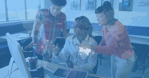 Team reviewing digital project on monitor with dotted world map overlay