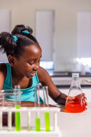 African american girl holding erlenmeyer flask and exploring chemistry in school lab