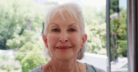 Elegant senior woman relaxing by window in sunlit home